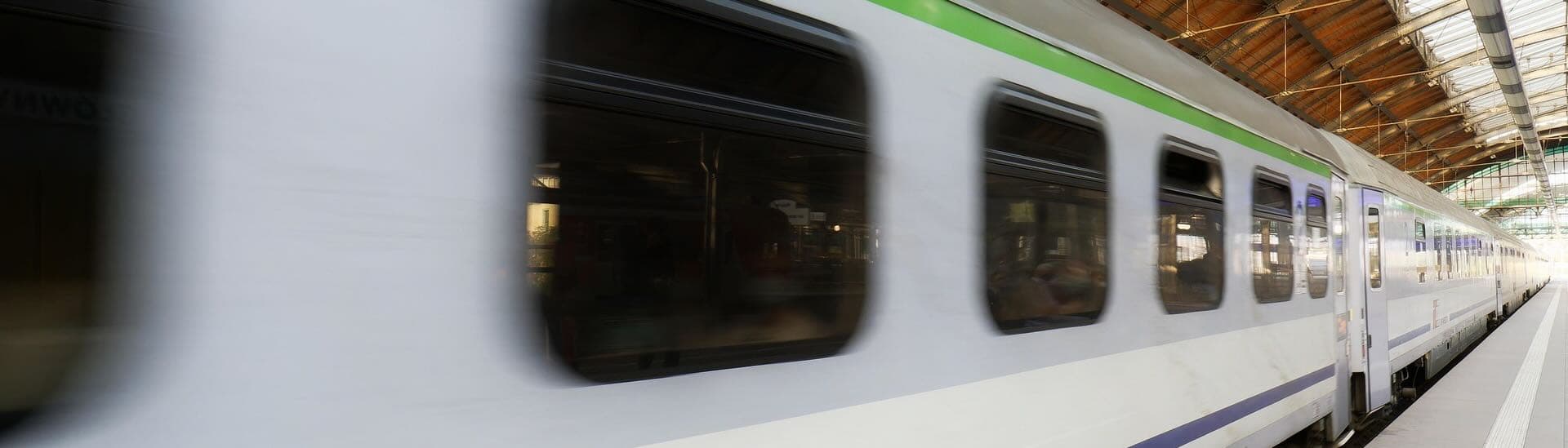 A passenger train pulling through a covered station platform.