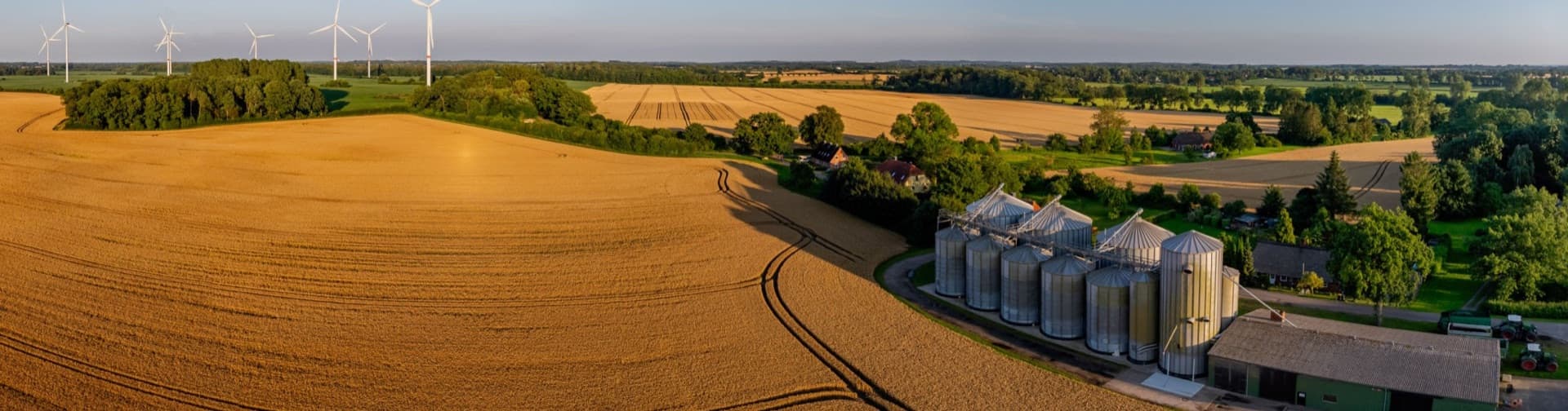 Aerial view of grain silos and elevators alongside a rail line at dusk.